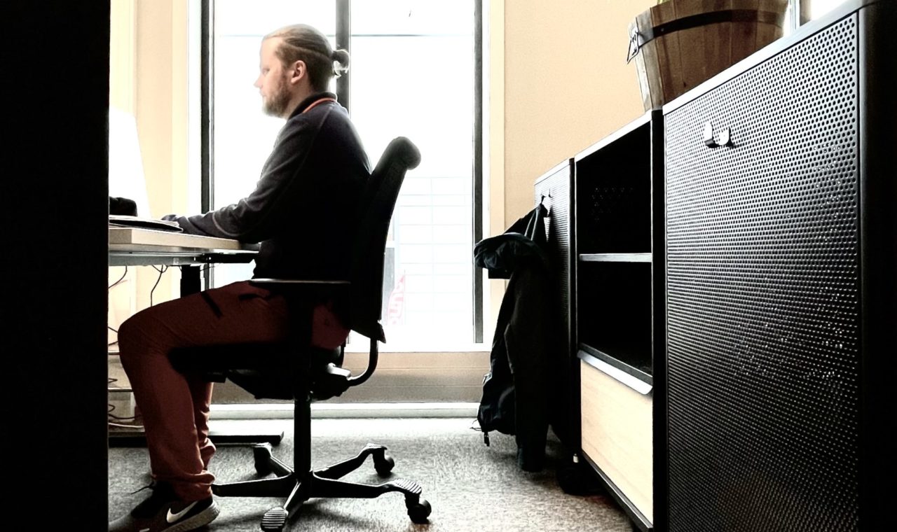 Bildet viser en mann som sitter og jobber ved et skrivebord