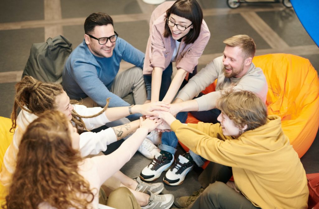 Bilde av en gruppe mennesker som samler hendene sine midt i gruppen