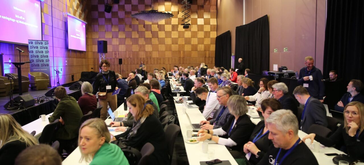 Bilde av mange mennesker i en konferansesal.