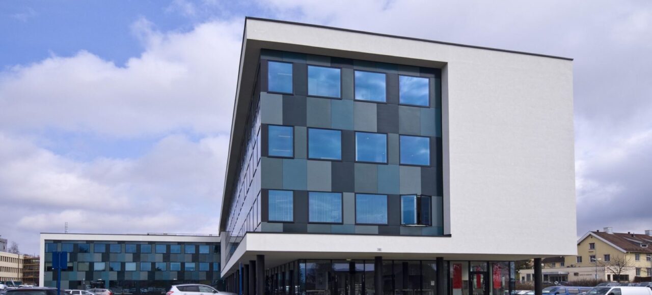 Bilde av hvitt bygg med mur og glassfasade