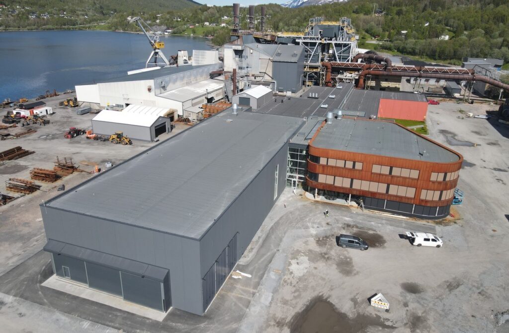 Oversiktsbilde av et fabrikkområde som har sjøen ved siden av.